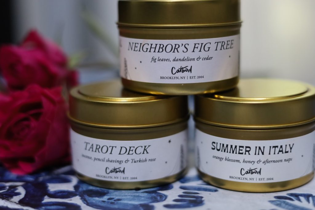 three candles stacked on top of one another scents are neighbor's fig tree, summer in italy, and tarot deck