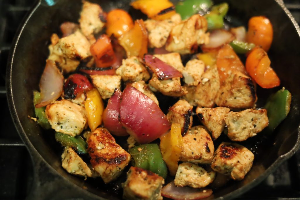 charred and grilled chicken and veggies in pan