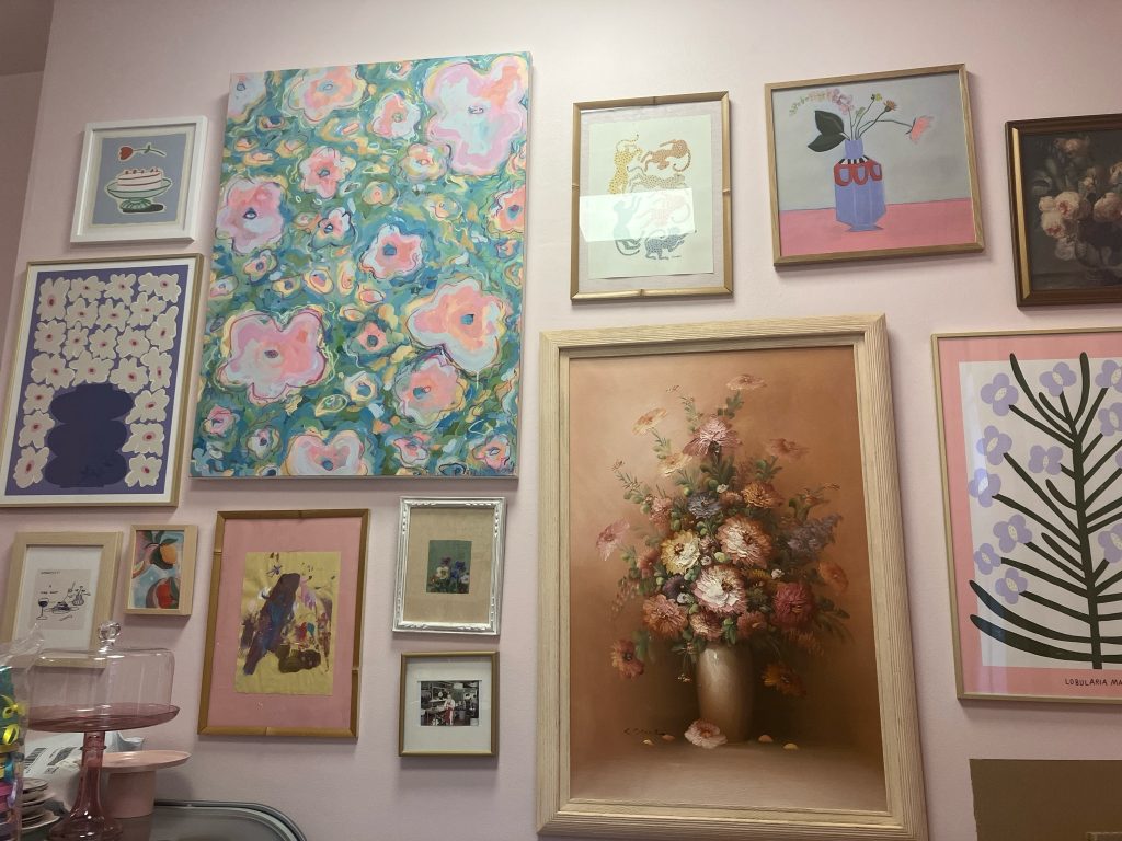 inside of a vintage cake bakery with pink walls and feminine artwork 